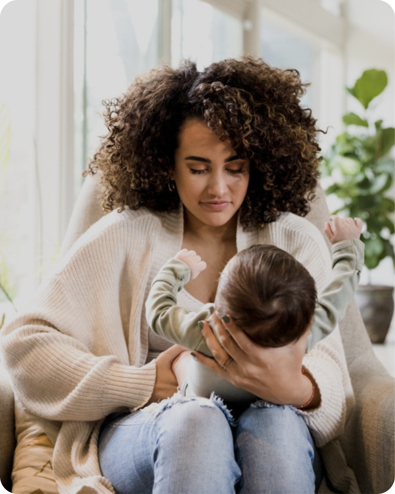 A pregnant woman on a couch holding her baby