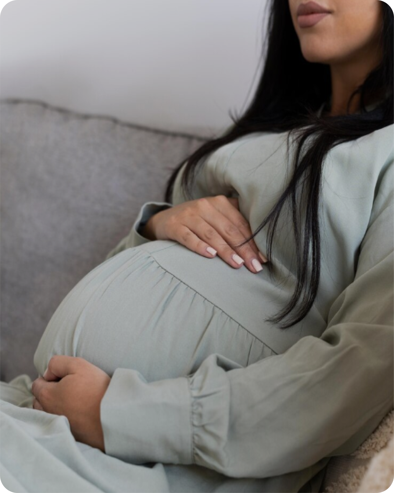 A pregnant woman on a couch holding her belly